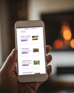 A hand holds a phone displaying the DealMagik app's "Specials" menu, showing various food items.