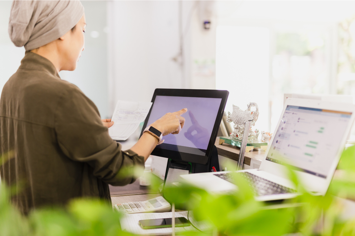 Small business owner using a touchscreen POS system to manage floral order processing and deliveries.